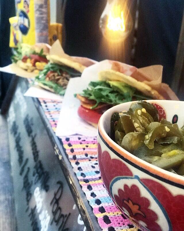 Schale mit Jalapeños und Arepas im Hintergrund — Detail vom Cubita-Stand mit warmem Edison-Licht