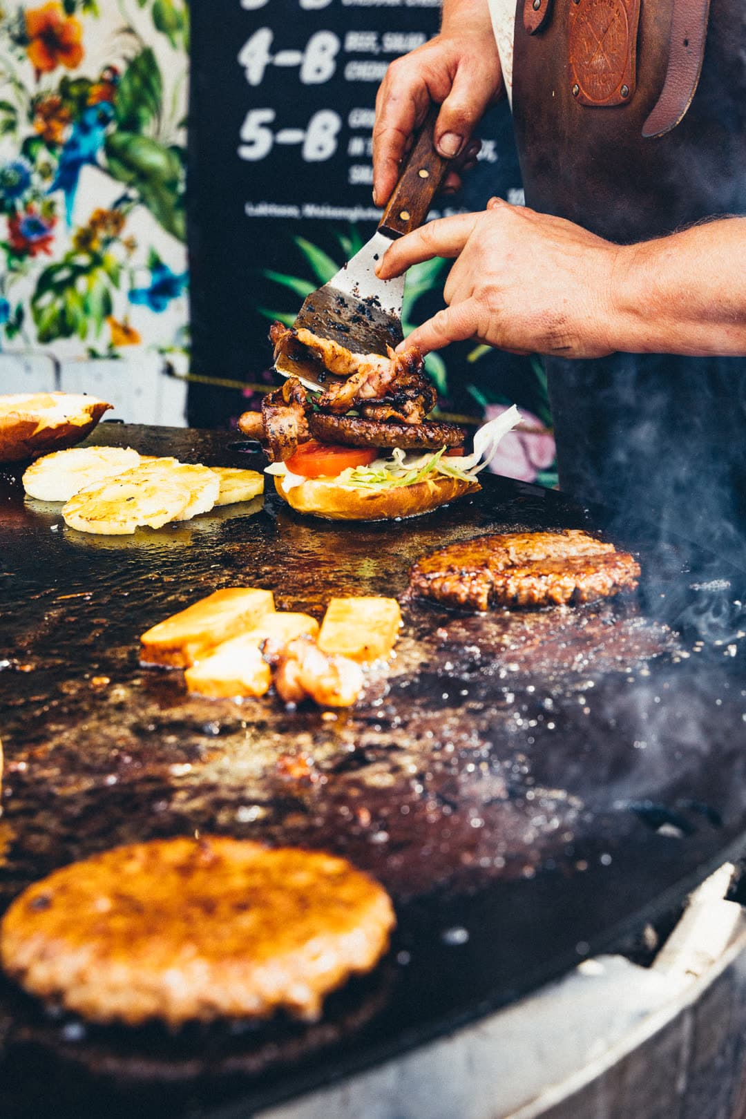 FoodFighter Food-Artist belegt Brioche mit frisch gegrilltem Patty und Bacon direkt auf der Plancha