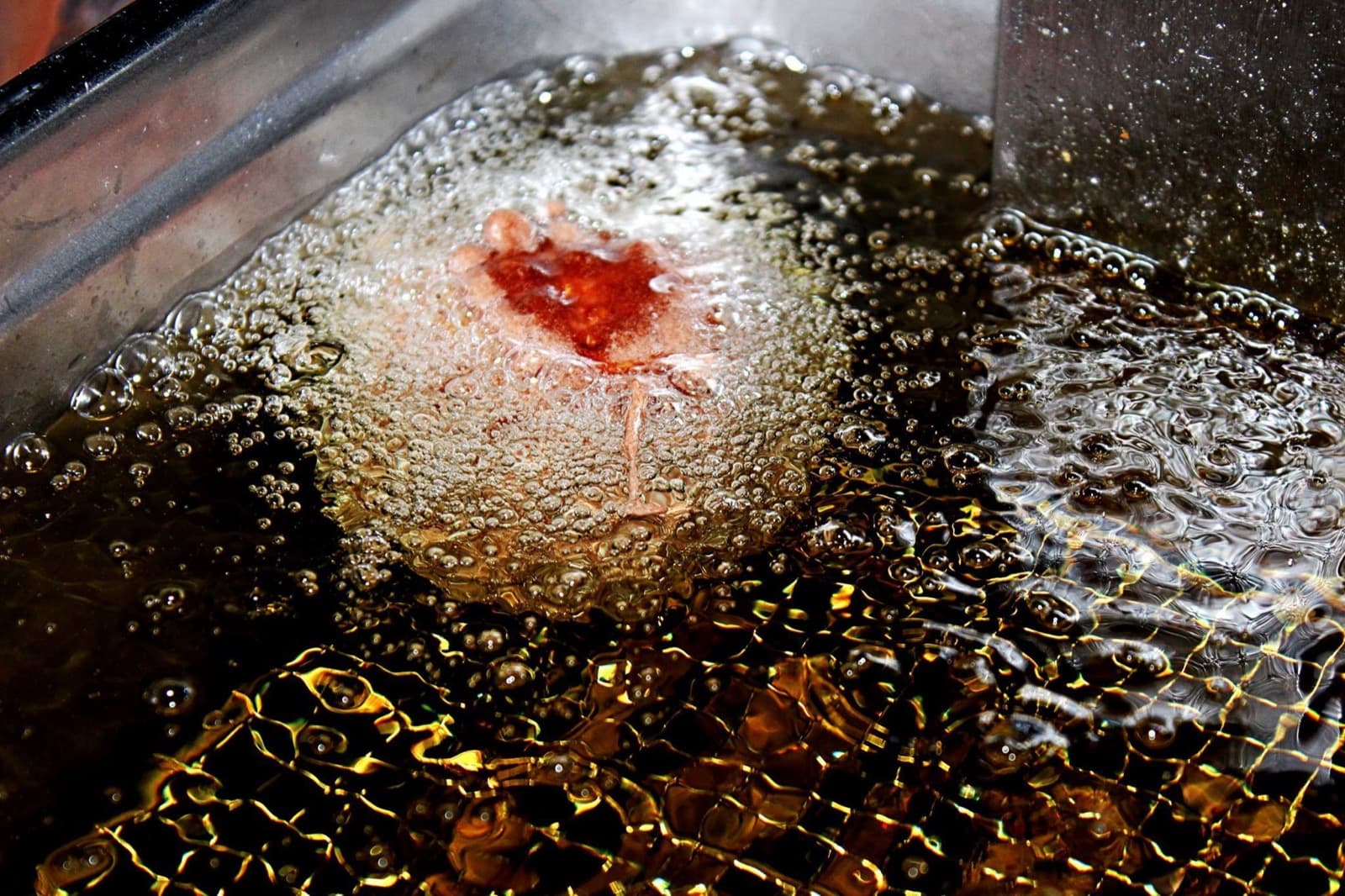 Frittiertes Eis — goldene Kugel im heißen Öl, außen knusprig, innen eiskalt